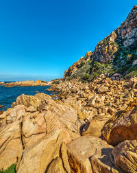 Rock formations in sea against clear blue sky