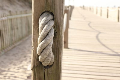Close-up of rope tied to wooden post. 
