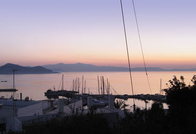 Sailboats moored in marina at sunset