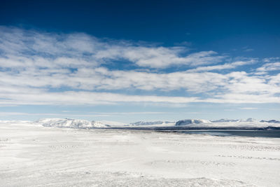 Scenic view of snow covered mountains against cloudy sky