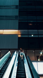 Low angle view of woman on escalator in building