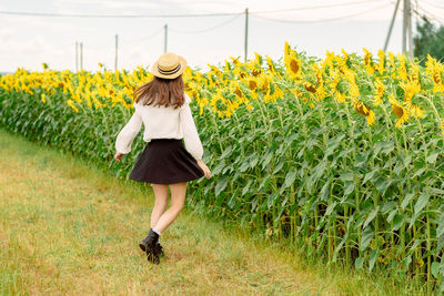 Full length of woman with yellow flowers in field