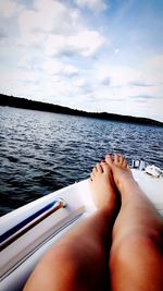 Low section of woman on boat in sea against sky