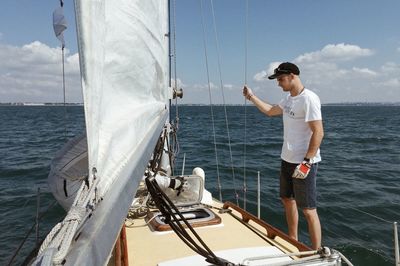 Full length of man standing on boat deck in sea against sky