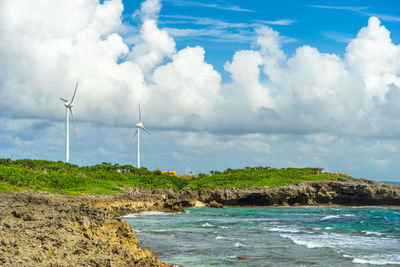 Wind turbines in sea against sky