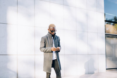 Handsome african boy with raincoat, sunglasses and mobile phone.