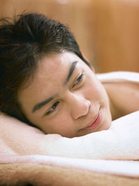 Close-up of young man lying on bed at health spa