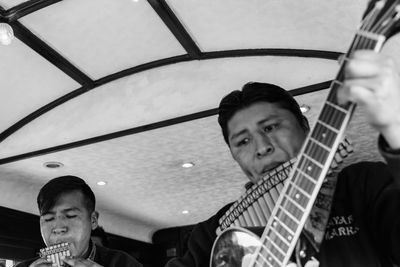 Men with panpipes and guitar performing in train