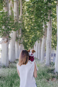 Rear view of woman with dog standing against plants