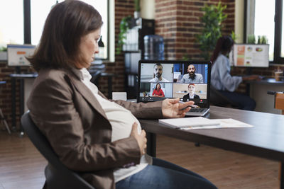 Pregnant businesswoman talking on video conference