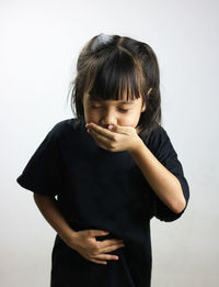 Girl vomiting while standing against white background