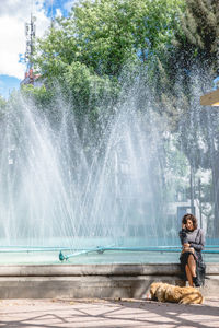 Man splashing water fountain against sky