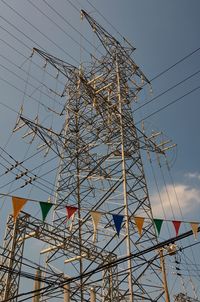 Low angle view of colorful bunting by electricity pylon