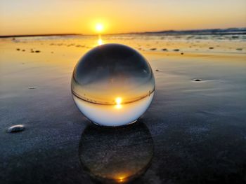 Close-up of water on beach against sunset sky