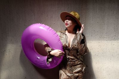 Woman holding inflatable ring while standing against wall