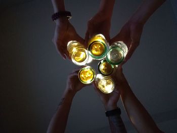 Cropped hands of friends toasting drinks against ceiling