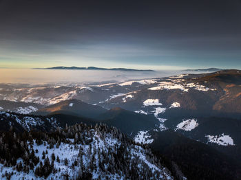 Aerial view of snowcapped mountains against sky during winter