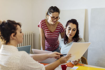 Young females with papers coworking on business startup