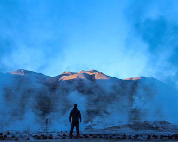 Rear view of man standing on mountain against sky