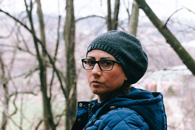 Portrait of mature woman wearing warm clothing while hiking in forest