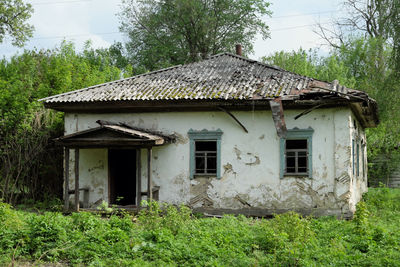 Abandoned house on field against trees