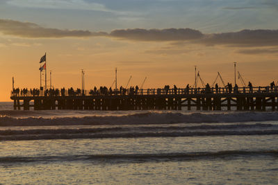Pier in sea at sunset