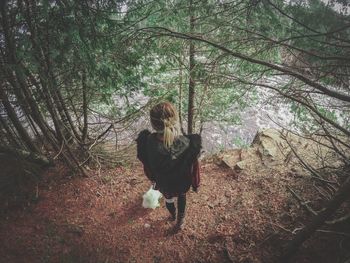 Woman standing by tree in forest