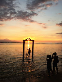 Silhouette women and man on beach during sunset