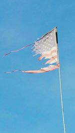 Low angle view of flag against clear blue sky