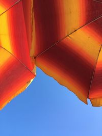 Low angle view of orange umbrellas against sky