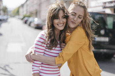 Two girlfriends embracing in the city