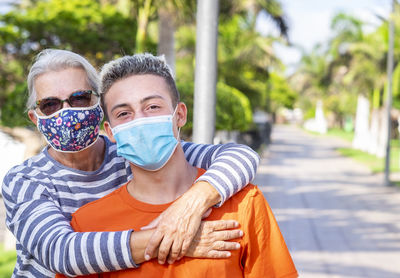 Portrait of grandmother and grandson wearing mask standing outdoors