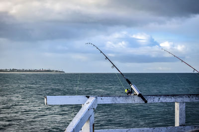 Man fishing in sea against sky