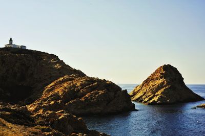 Rock formations in sea against clear sky