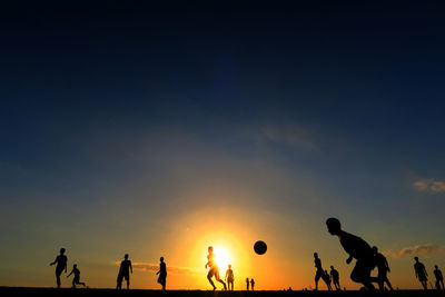 Silhouette people playing soccer sky during sunset