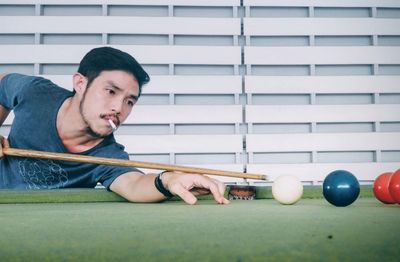 Man smoking cigarette while playing snooker