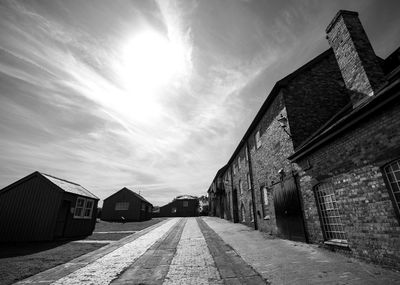 Empty footpath by building on sunny day