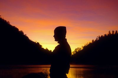 Silhouette man standing against orange sky during sunset