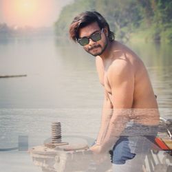 Portrait of young man wearing sunglasses at lake