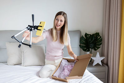 Portrait of young woman sitting on bed at home