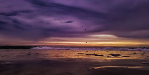Scenic view of sea against dramatic sky during sunset