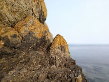 Close-up of rock formation by sea against sky