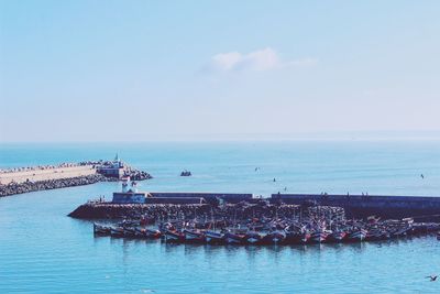 Boats moored at harbor in sea against sky