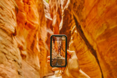 Young man's hand taking picture of slot canyons in kanarra falls