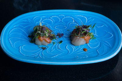 Raw scallop dish served with herbs and sauce. japanese cuisine restaurant background