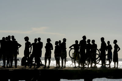 Silhouette of young people jumping from the crush bridge at the yellow sunset.