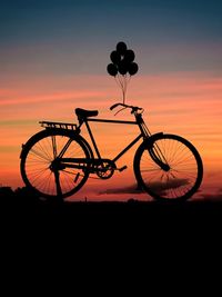 Silhouette bicycle on field against sky during sunset