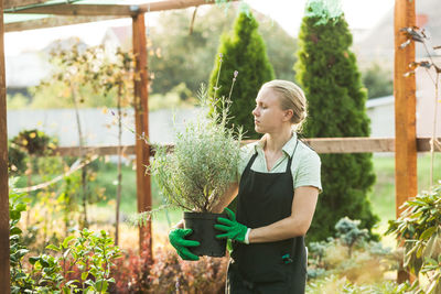 Full length of woman standing on potted plant