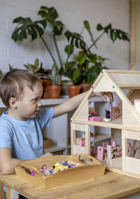 Cute boy playing with model house at home