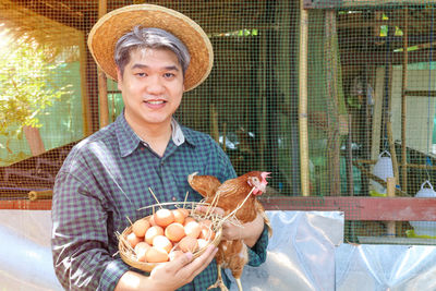 Portrait of man holding bird in cage